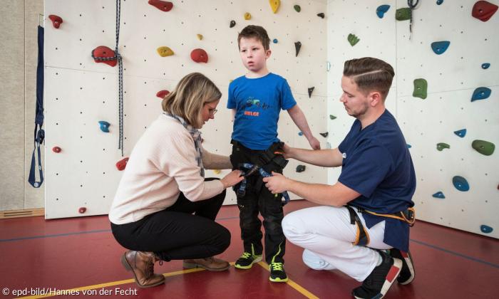 Ein kleiner Junge mit zwei Erwachsenen in einer Sporthalle