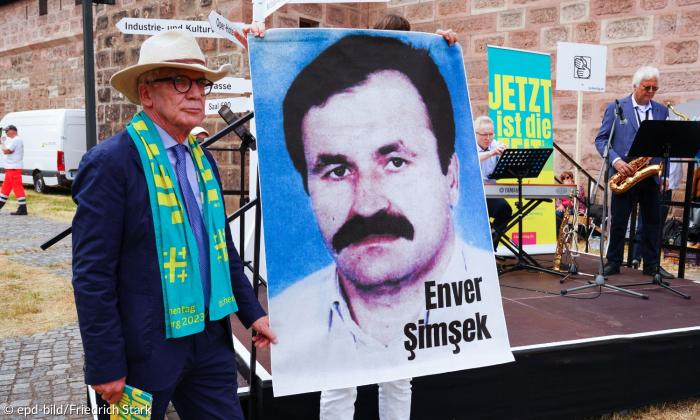 Ein Mann neben einem Plakat