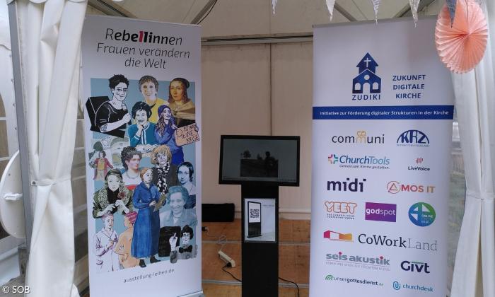 Der Infoscreen zwischen Plakaten am Stand