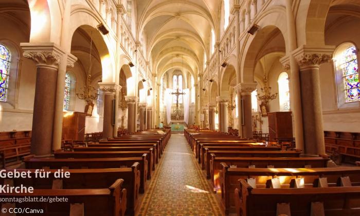 Eine Kirche von innen, mit Bänken und einem Kreuz.