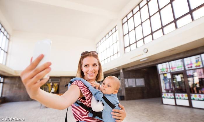 Eine Frau mit einem Baby auf dem Arm macht ein Selfie