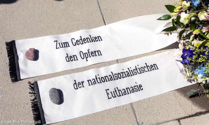 Auf zwei am Boden ausgebreiteten Bannern steht: "Zum Gedenken an den Opfern der nationalsozialistischen Euthanasie"