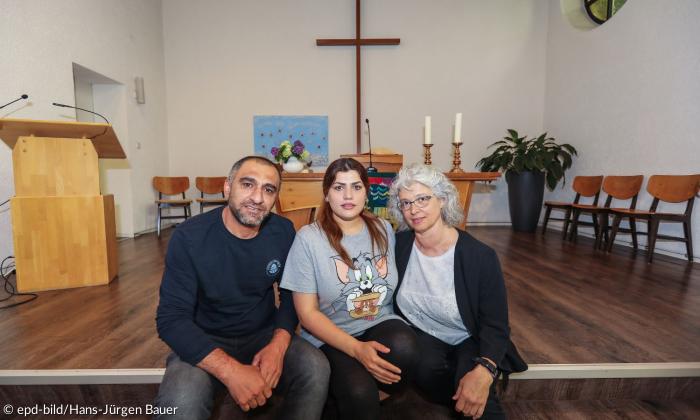 Zwei Frauen und ein Mann sitzen vor einem Altar