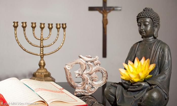 Kronleuchter, Kruzifix, Buddhafigur, Koran, OM-Symbol