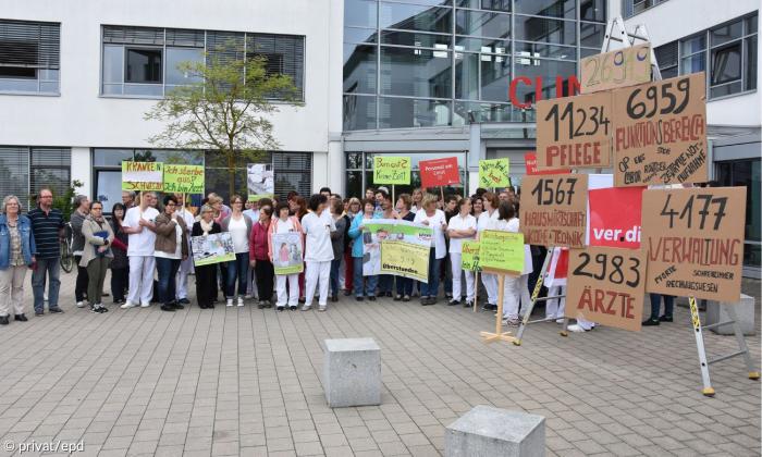 Menschen mit Schildern vor einer Klinik