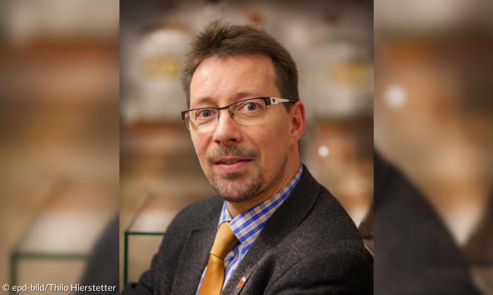 Ein Mann mit Brille im Anzug und Krawatte
