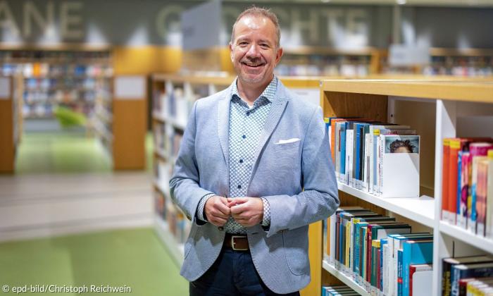 Ein Mann im Anzug steht vor Bücherregalen