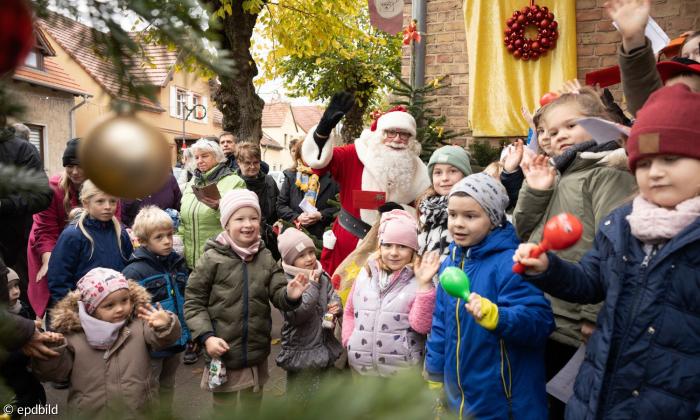 Eine Gruppe von Kindern steht neben den Weihnachtsmann 