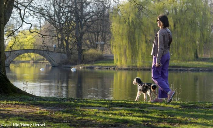 Eine Frau mit einem Hund am Flussufer