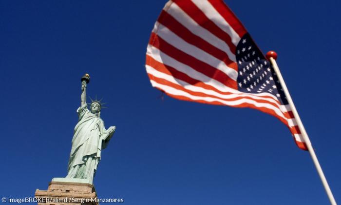 Die Freiheitsstatue und eine amerikanische Fahne