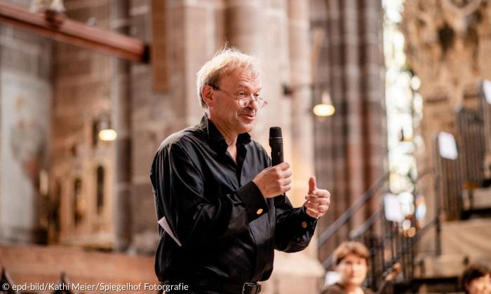 Ein Mann hält ein Mikrofon, er steht in einer Kirche