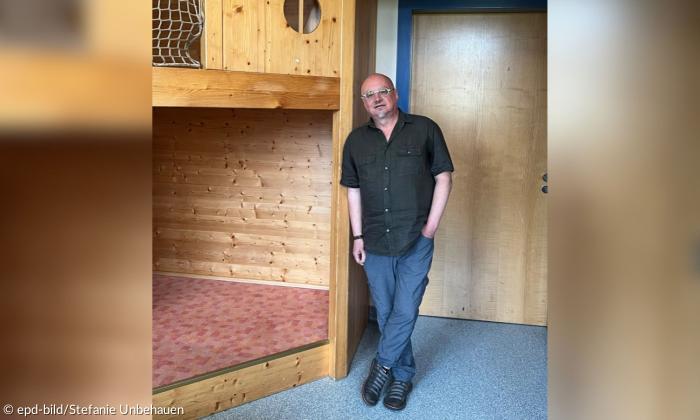 Ein Mann steht neben einem Holzaufbau