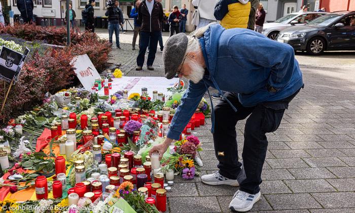 Ein Mann stellt eine Kerze auf, es stehen schon viele Kerzen auf der Straße
