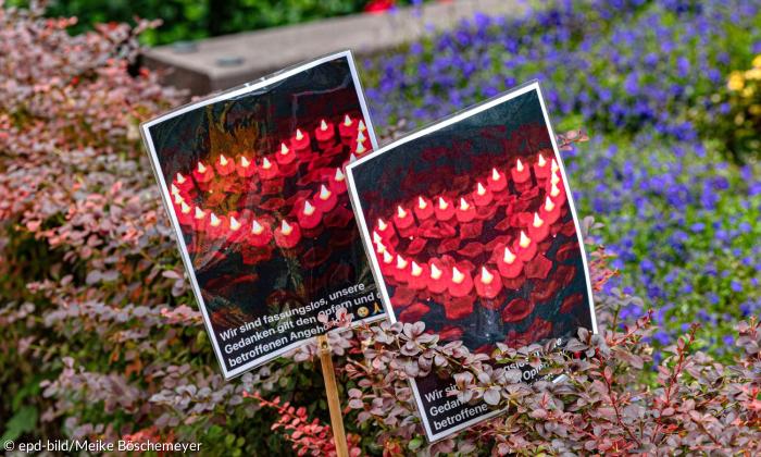 Blumen und zwei Plakate, auf denen aus Kerzen geformte Herzen zu sehen sind