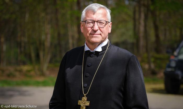 Ein Mann mit grauem Haar und Kreuzkette