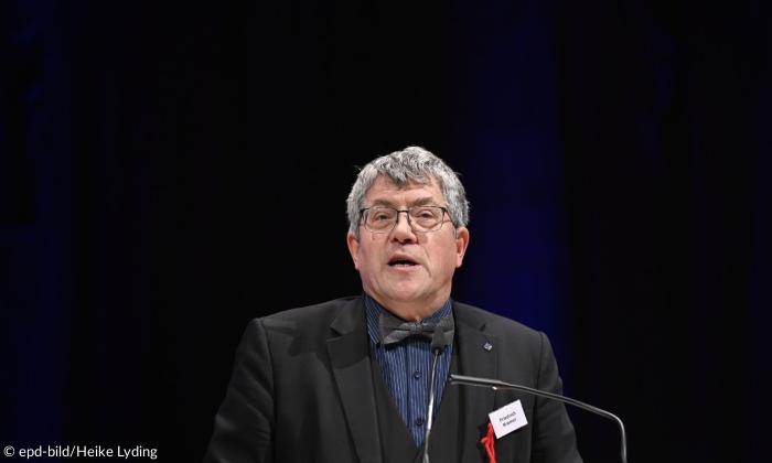 Ein Mann mit Brille und Fliege im schwarzen Anzug