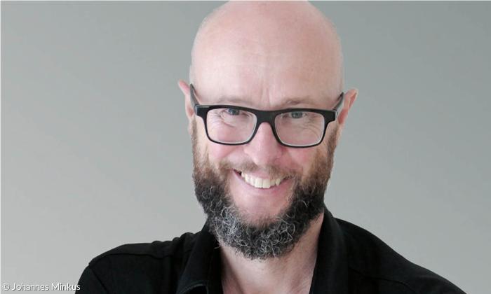 Ein Mann mit Brille und Bart lächelt