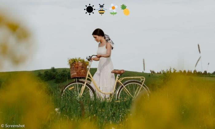 Eine Frau mit Fahrrad in einem weißen Kleid mit Emojis