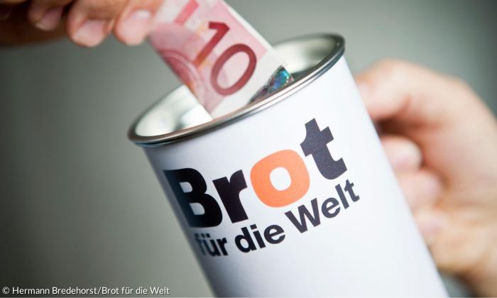 Eine Spendendose mit der Aufschrift "Brot für die Welt" und ein 10 Euro Schein