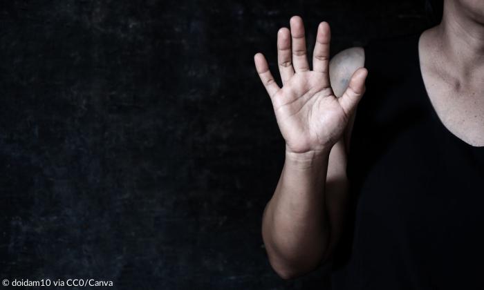 Eine Frau hebt abwehrend die Hand