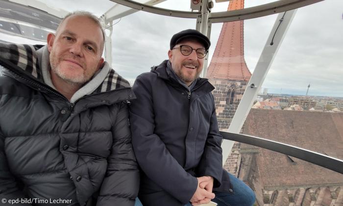 Zwei Männer sitzen warm angezogen in einer Riesenrad-Gondel