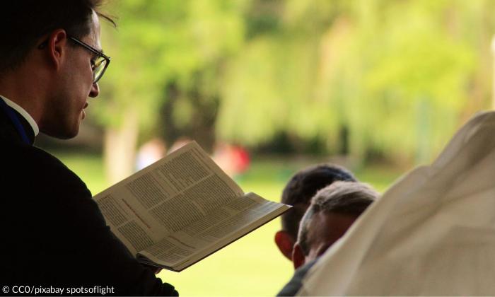 Ein Mann mit Brille liest aus der Bibel