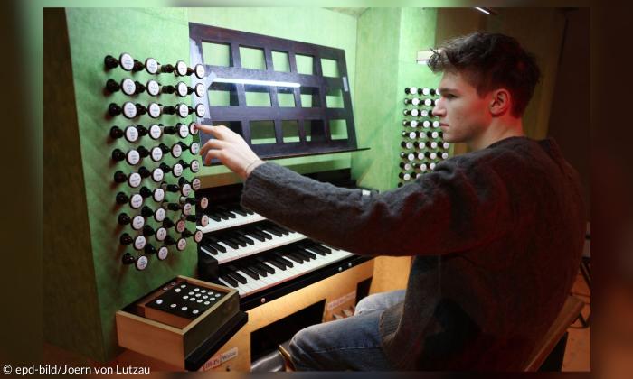 Ein junger Mann sitzt an einer Orgel
