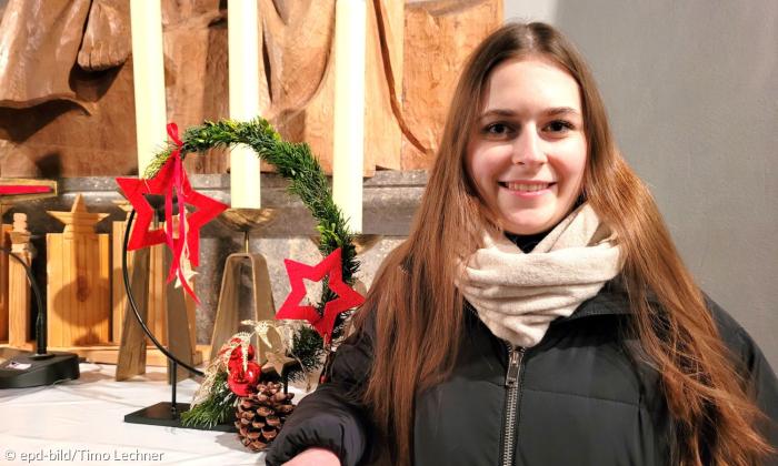 Eine junge Frau steht vor einem weihnachtlich geschmückten Altar