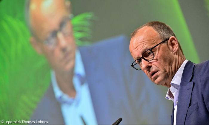 Ein Mann mit Brille und Hemd spricht in ein Mikrofon