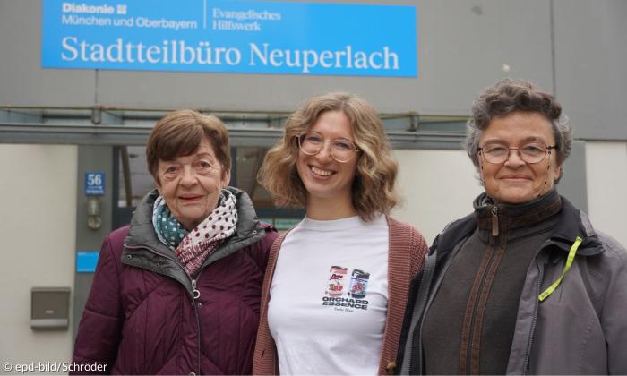 Drei Frauen stehen lächelnd vor einem Gebäude der Diakonie