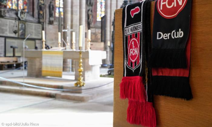 Ein Fußballschal des 1. FC Nürnberg hängt über einer Bank in der Kirche