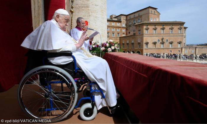 Ein Mann im Papstgewand im Rollstuhl auf einem Balkon