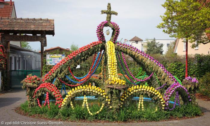Viele bunte Eier sind um einen Brunnen gruppiert