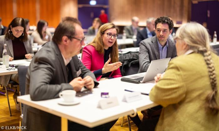 Menschen sitzen an einem Tisch und diskutieren