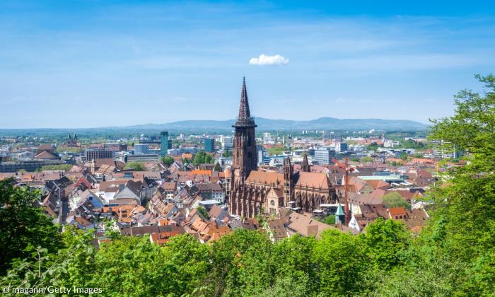 Blick auf eine Stadt mit einer großen Kirche, im Hintergrund Berge