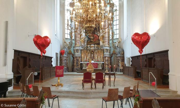 Eine Kirche, in der rote herzförmige Luftballons schweben
