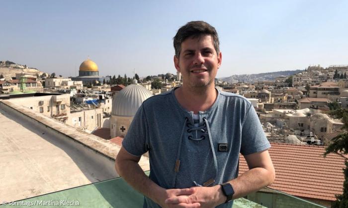 Ein Mann steht an einer Ballustrade, hinter ihm der Felsendom von Jerusalem