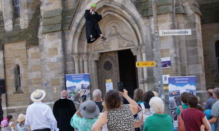 Ein Mann im Talar seilt sich an einer Kirche ab