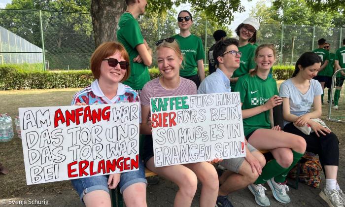 Menschen mit Schildern an einem Fußballplatz