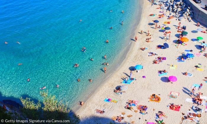 Ein Strand mit vielen Schirmen und Menschen von oben gesehen