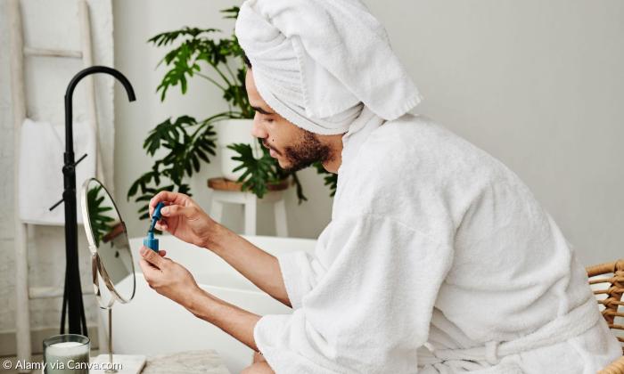 Ein junger Mann im Bademantel lackiert sich die Fingernägel