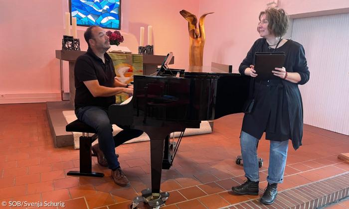 Ein Mann sitzt am Klavier, eine Frau lehnt daran