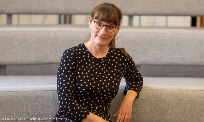 Julia Wunderlich sitzt auf einem Sessel und schaut in die Kamera.