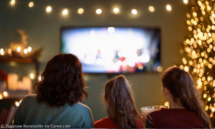 Drei Personen sitzen vor dem Fernseher