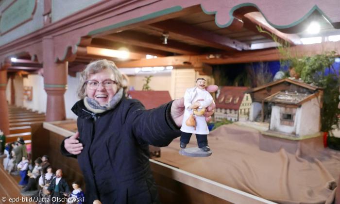 Eine Frau hält eine Figur in die Kamera