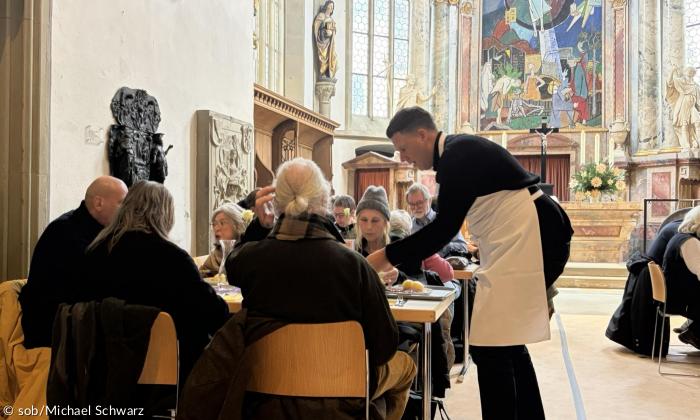 Menschen sitzen an Tischen in einer Kirche