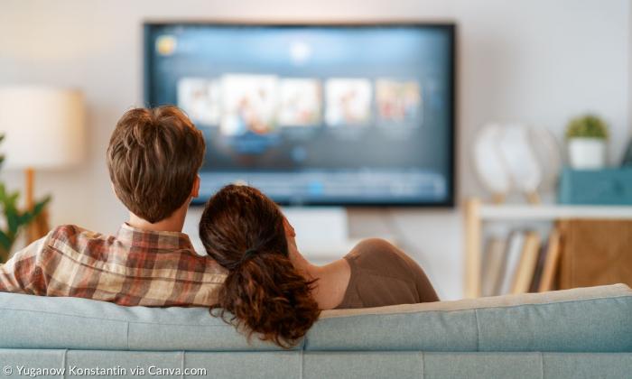 Zwei Menschen sitzen auf der Couch und schauen fern