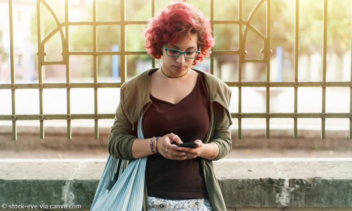 Frau mit roten Haaren am Smartphone unterwegs