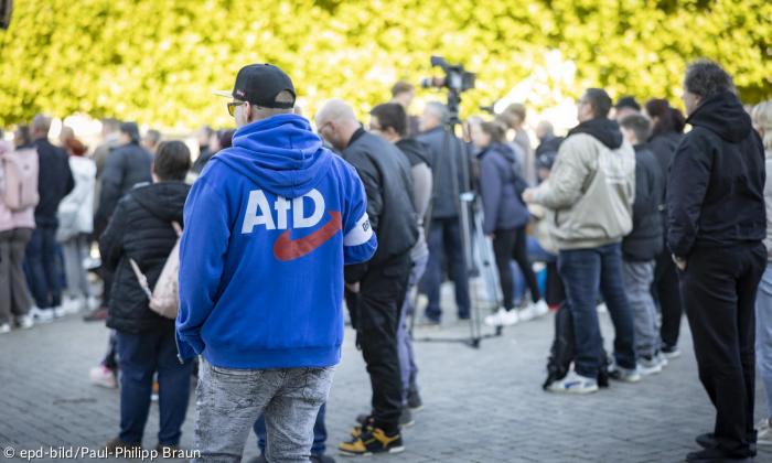 Ein Mann mit einer blauen Jacke, auf die das AfD-Logo gedruckt ist