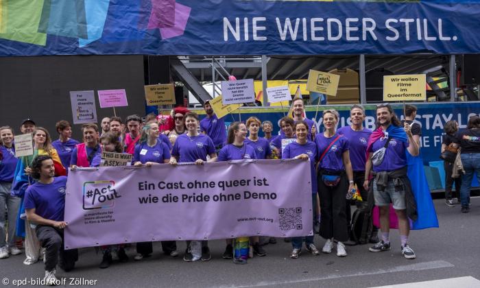 Menschen in lila vor einem Schriftzug: "Nie wieder still."